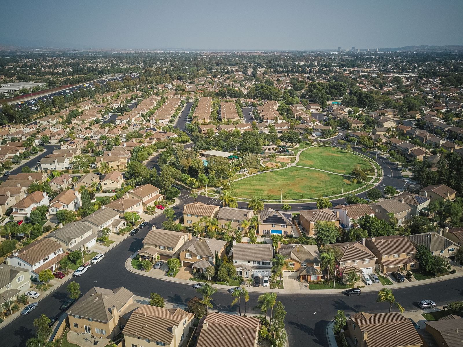 Aerial view of a neighborhood of two-storey homes around a large oval park