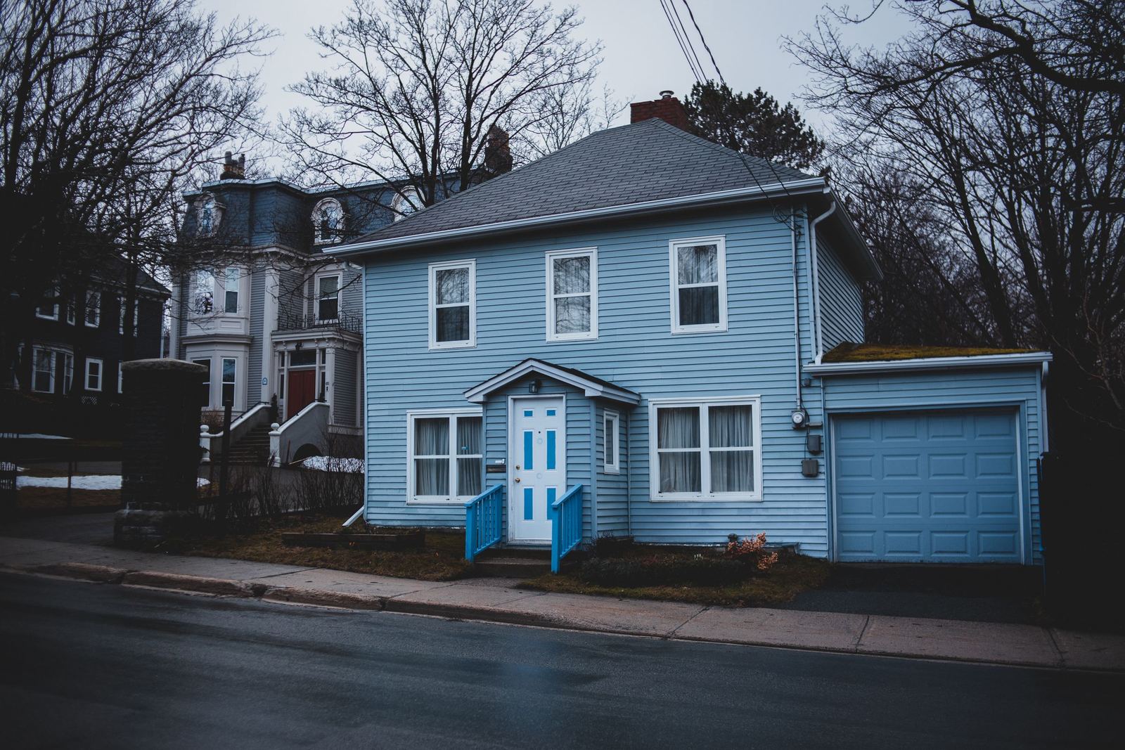 Light-blue clapboard house with an attached garage on a quiet street