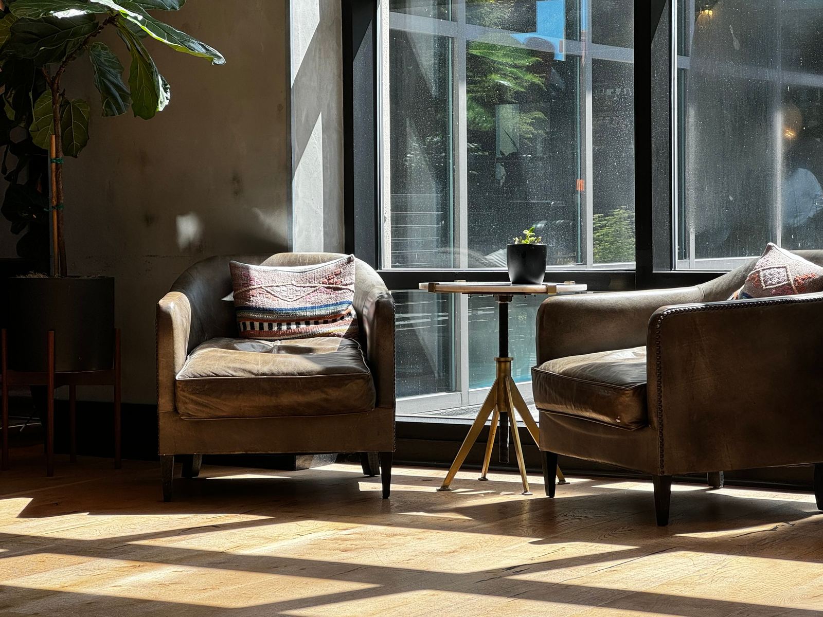 Two leather armchairs beside a tall window in afternoon sun